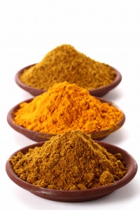 piles of bright Curry Powder and tumeric in teracotta dish